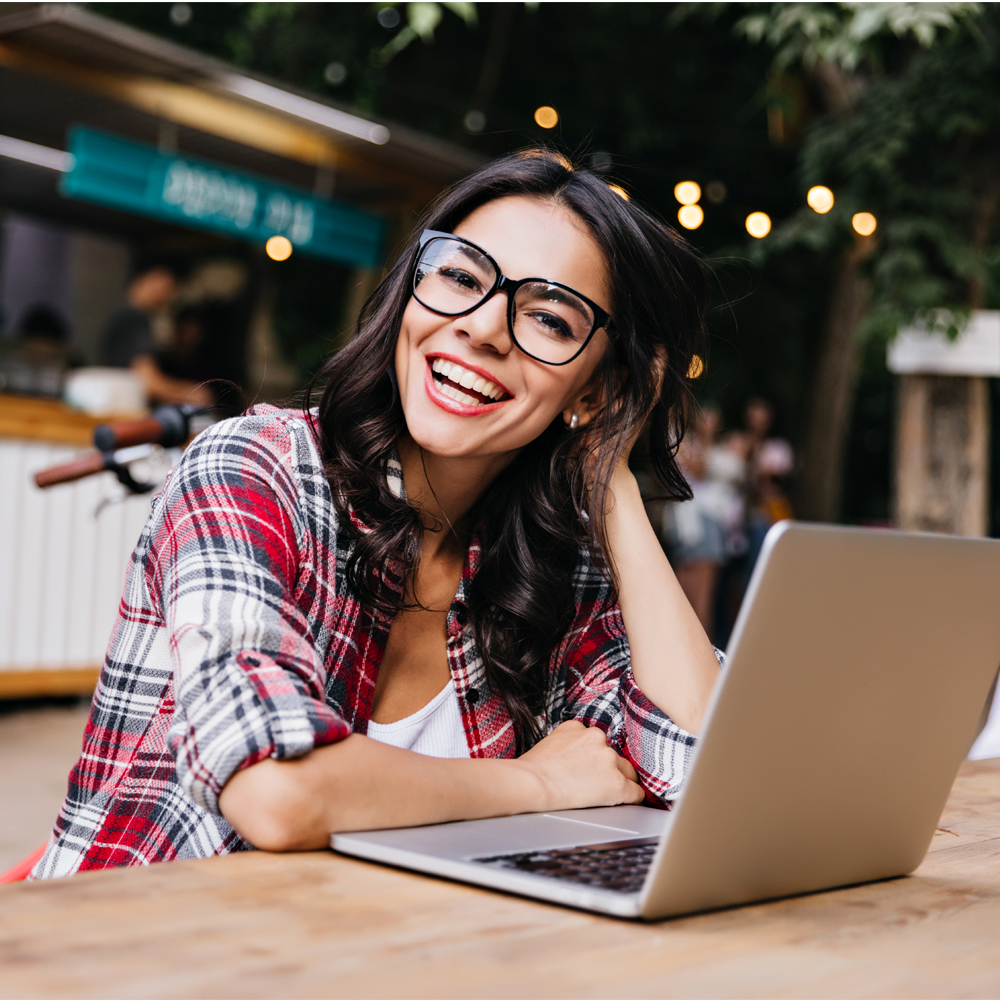 seguro viagem internacional, moça sorrindo enquanto usa o notebook