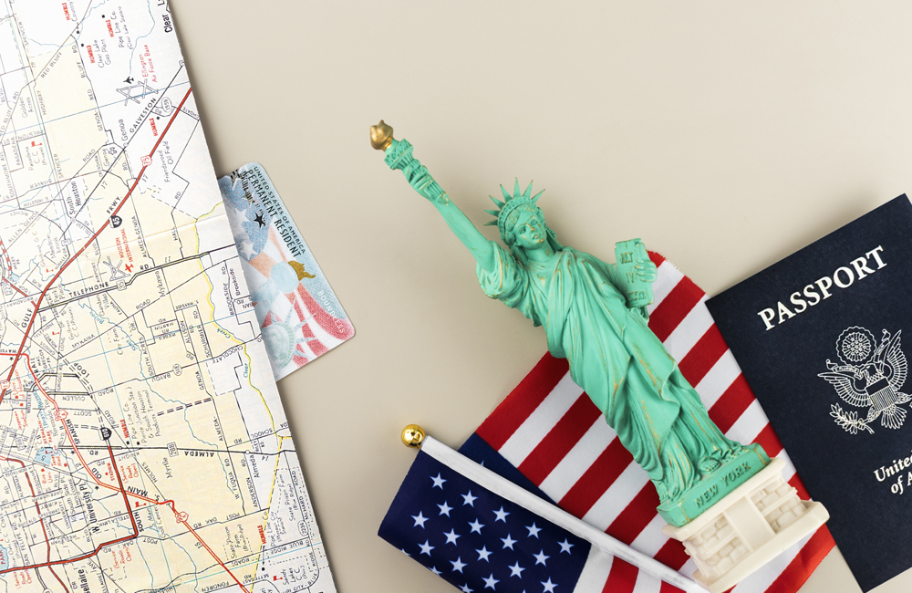 imagem com miniatura de uma estátua da liberdade, um passaporte, uma bandeira dos EUA e um mapa